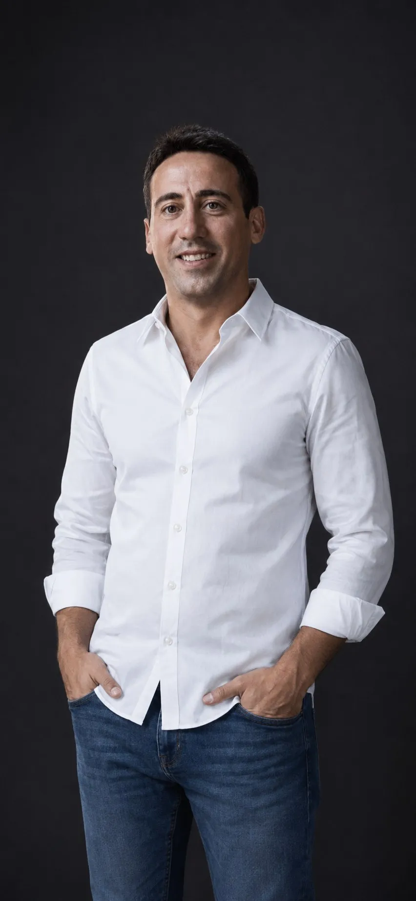 Manuel Liria, de cuerpo entero, con camisa blanca y vaqueros, sobre fondo gris oscuro
