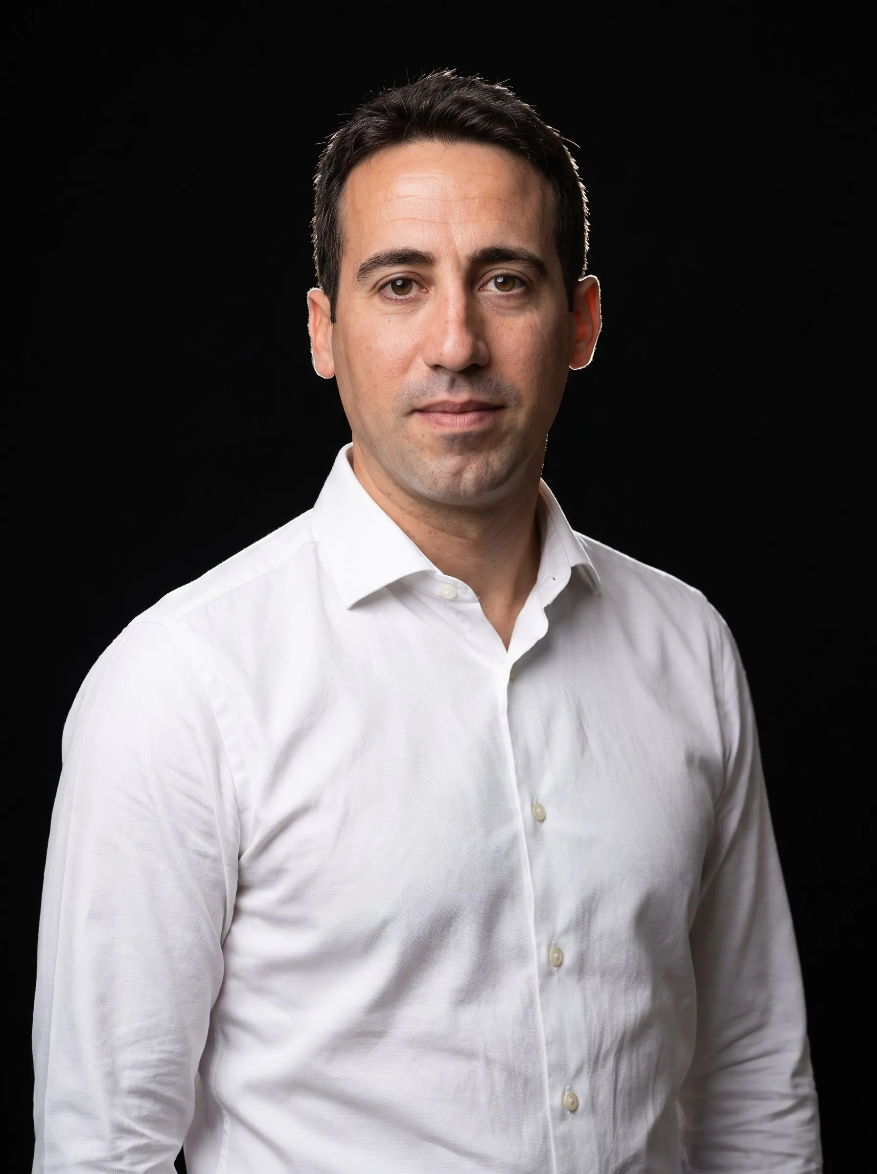Manuel Liria, de tres cuartos, con camisa blanca sobre fondo negro de estudio